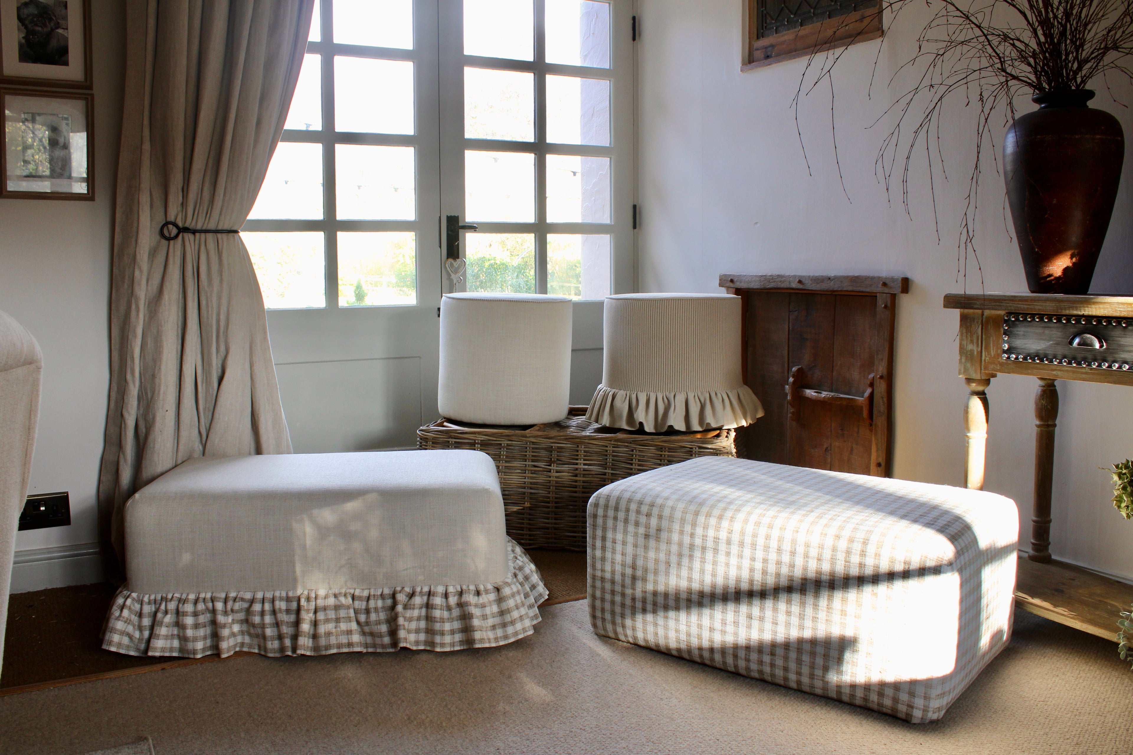 Living room with checkered ottoman and chair, lampshades, and curtains.