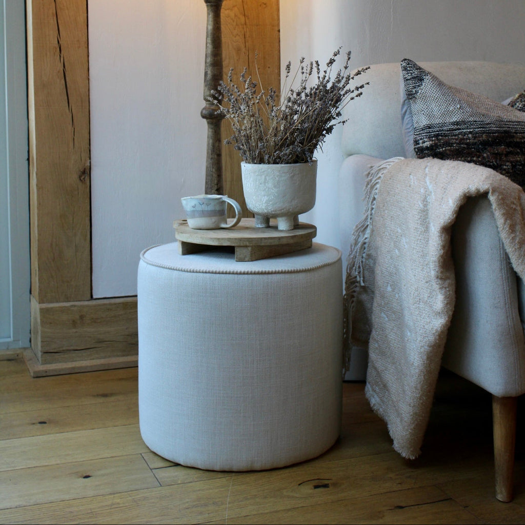 Round ottoman next to a lamp and sofa